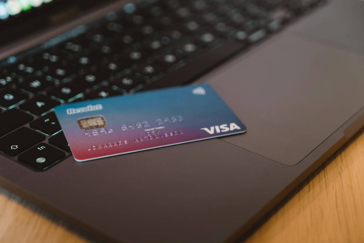 Woman checking laptop price drop while holding credit card for online store refund
